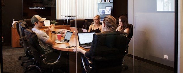 Business team collaborating in a conference room with laptops, discussing global translation services, technology, and cross-border communication strategies