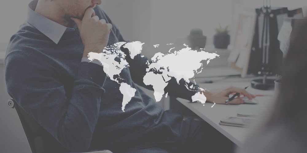 Business professional reviewing global market strategy with world map overlay, representing export translation services for international trade and global commerce.
