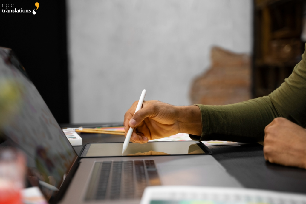 Designer using a digital tablet and stylus to review and format multilingual desktop publishing layouts.